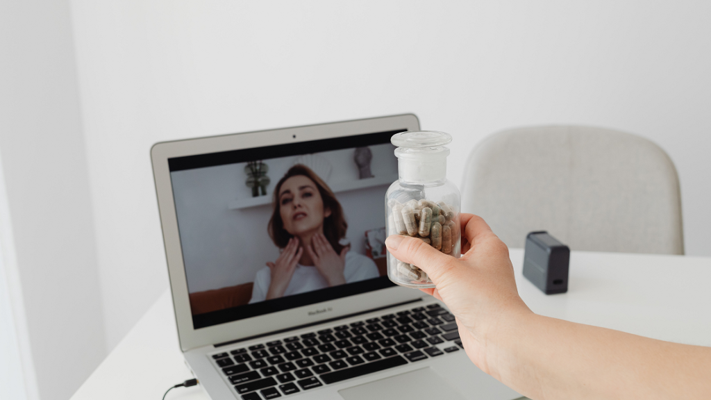 Medical professional holding medication bottle during an online medical consultation on a laptop, illustrating healthcare communication supported by video remote interpreting (VRI).